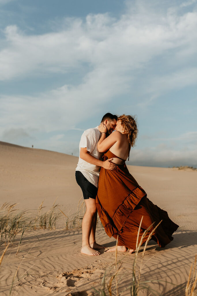 Couple posing during golden hour for their Silver Lake Sand Dunes engagement photos in MI