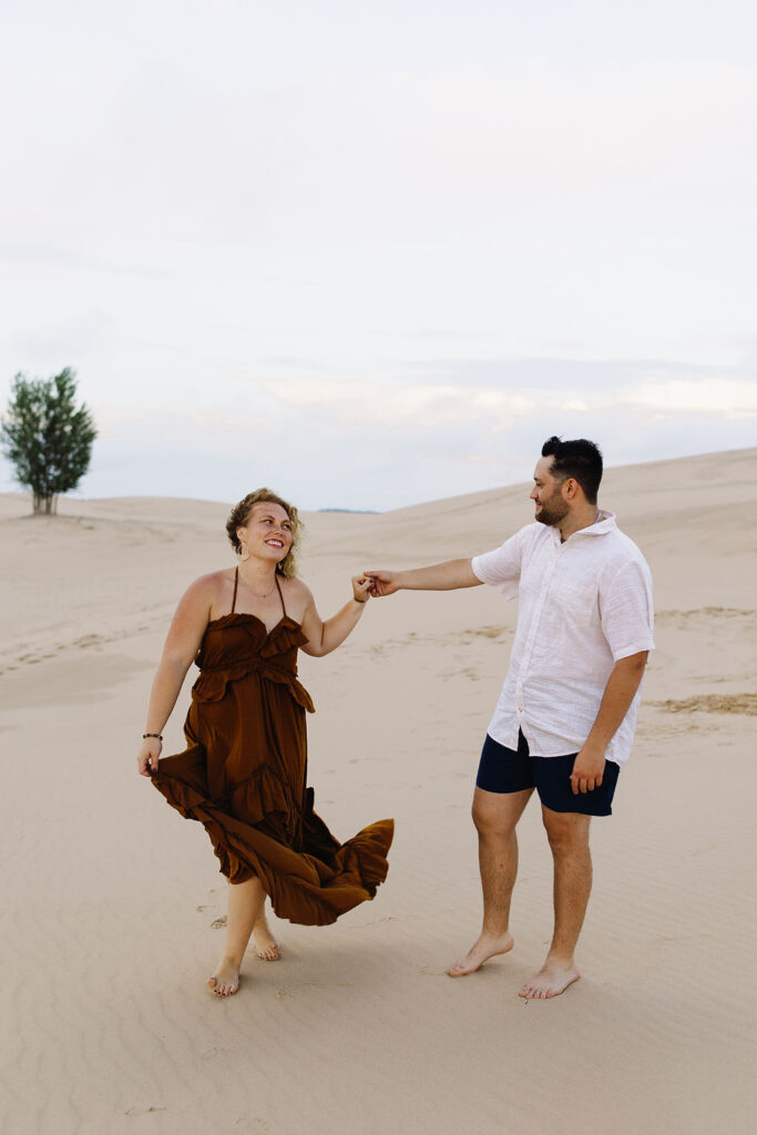 Couple being playful during their Michigan beach engagement shoot