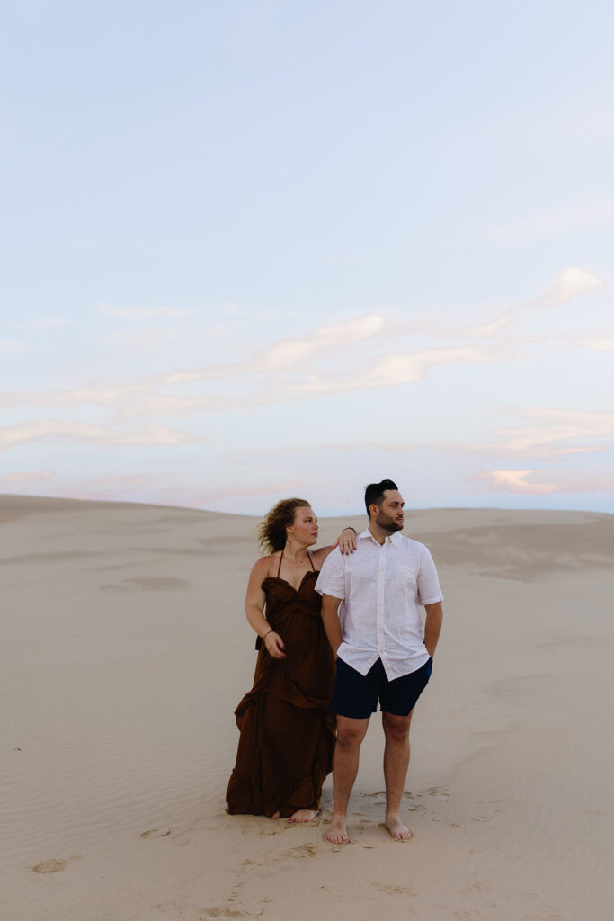 Couple posing on the beach for their Silver Lake Sand Dunes engagement photos