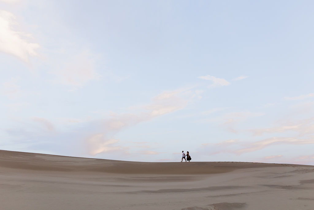 Couple walking along the beach for their Silver Lake Sand Dunes engagement photos