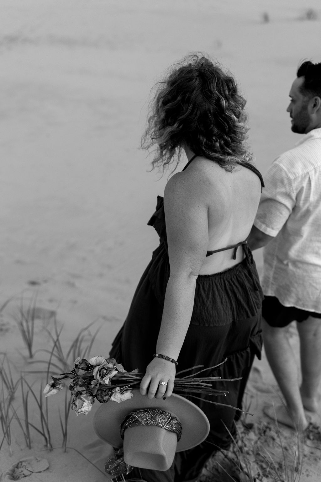 Black and white photo of a couple walking along the beach