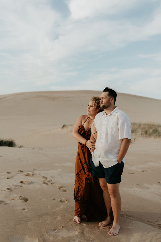 Couple posing during golden hour for their Silver Lake Sand Dunes engagement photos in MI