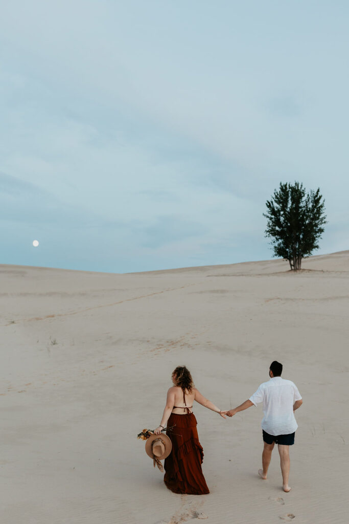 Couple walking the beach during their Silver Lake Sand Dunes engagement photos