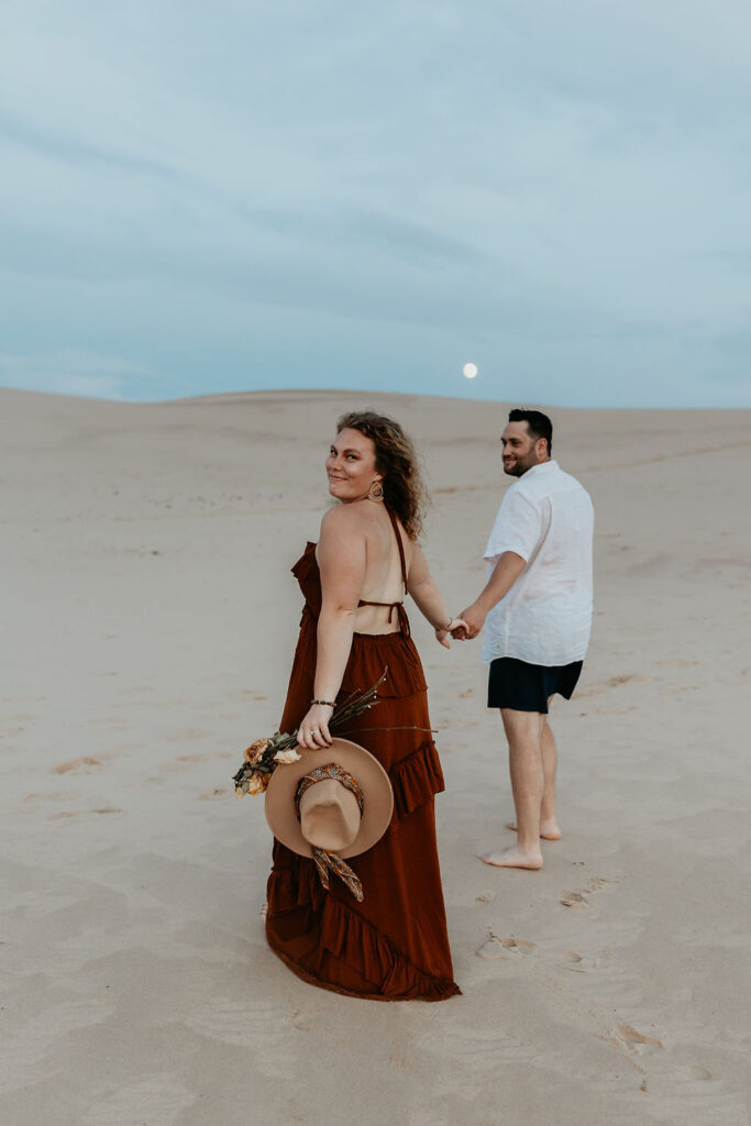 Couple walking the beach during their Silver Lake Sand Dunes engagement photos