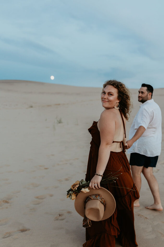 Couple walking the beach during their Silver Lake Sand Dunes engagement photos