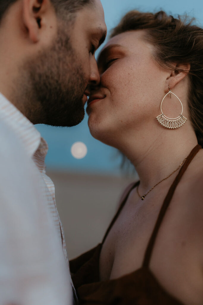 Couple kissing with the mood in between them during their Silver Lake Sand Dunes engagement photos