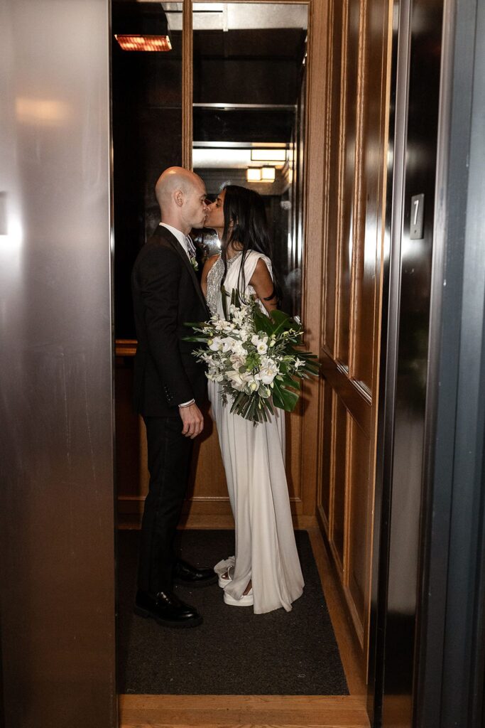 Bride and groom kissing in an elevator