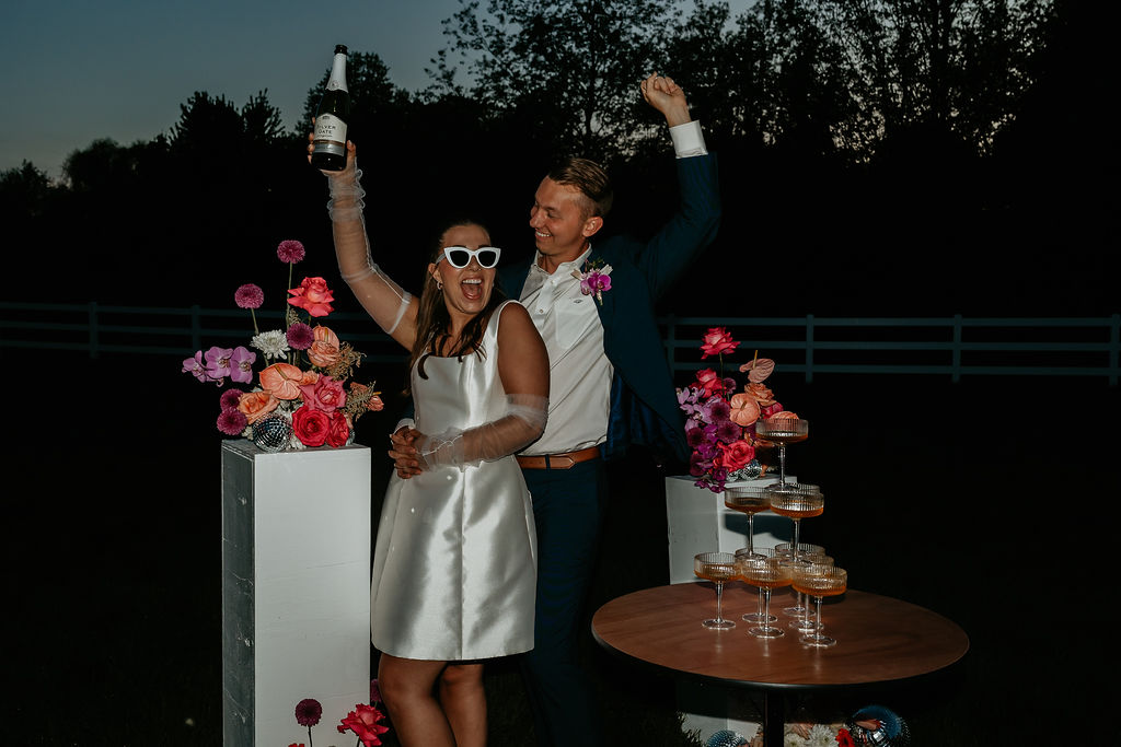 Bride and groom posing with their champagne tower