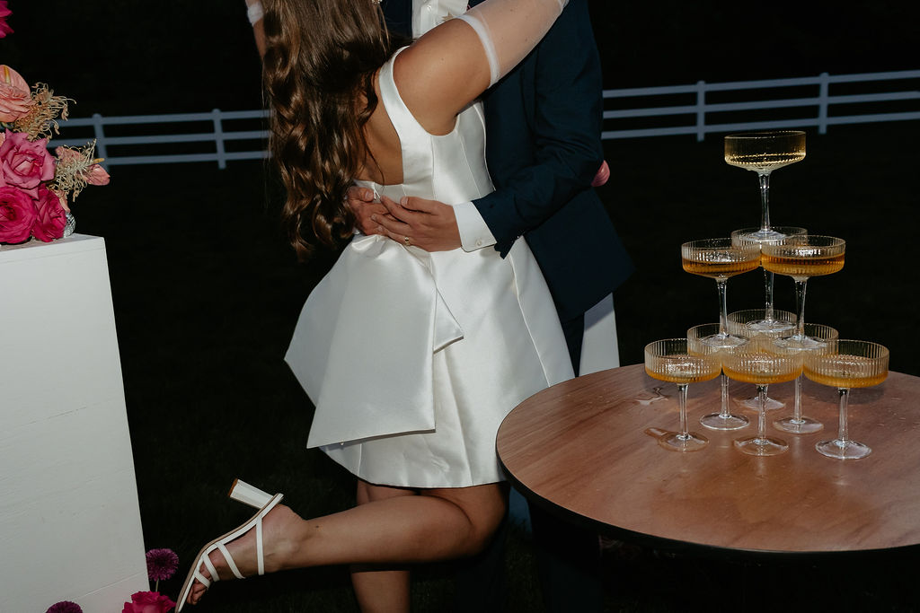 Bride and groom posing next to their champagne tower