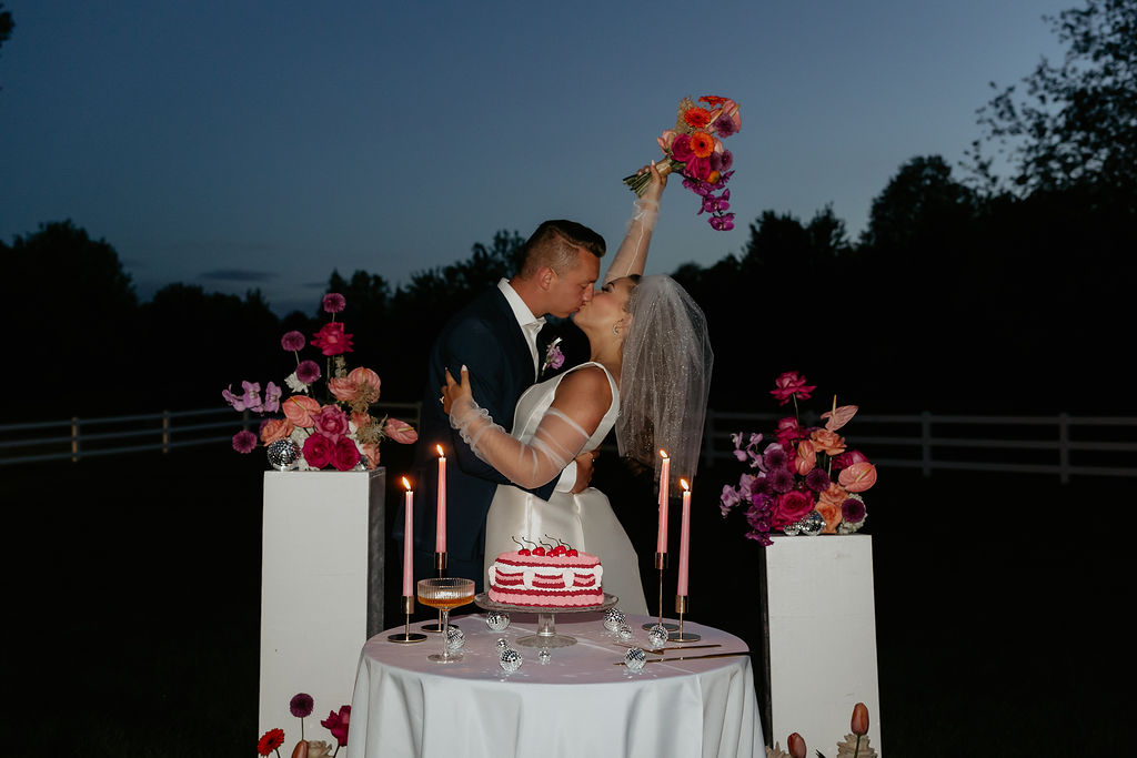 Bride and groom kissing at their cake table for their wedding reception flash photos