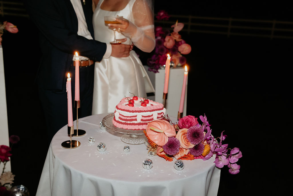 Bride and groom posing with champagne and a cake