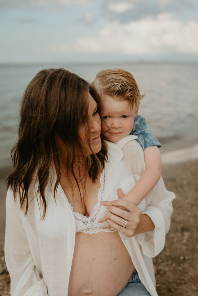 Mother and her son posing on the beach for her Michigan beach maternity photos on Lake Huron