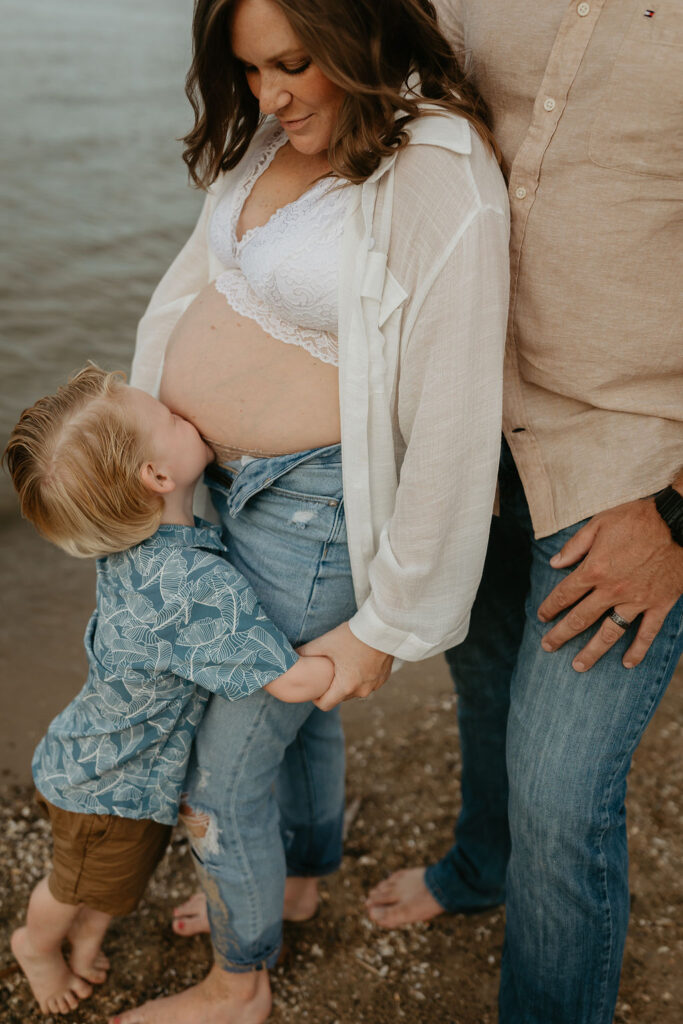 Family of three posing on the beach during their Michigan beach maternity photos on Lake Huron