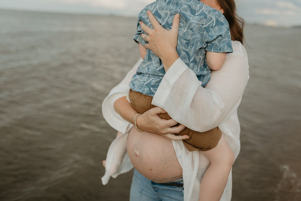 Mother holding her son during her Michigan Beach maternity photos on Lake Huron