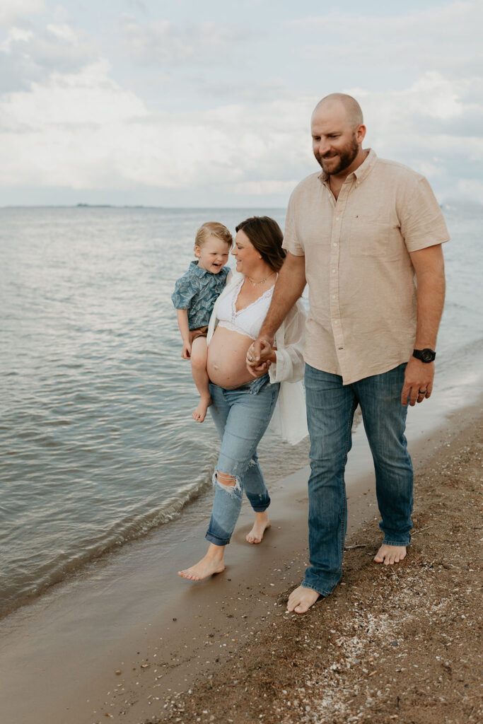 Family of three walking Lake Huron for their Michigan beach maternity photos